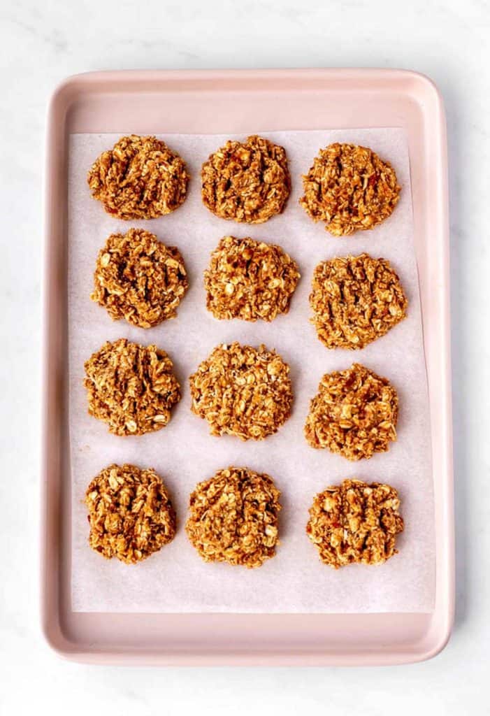 The unbaked 3 ingredient applesauce oatmeal cookies on a pink baking sheet.