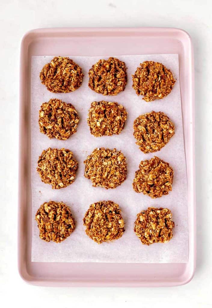 The baked applesauce oatmeal cookies on a pink baking sheet.