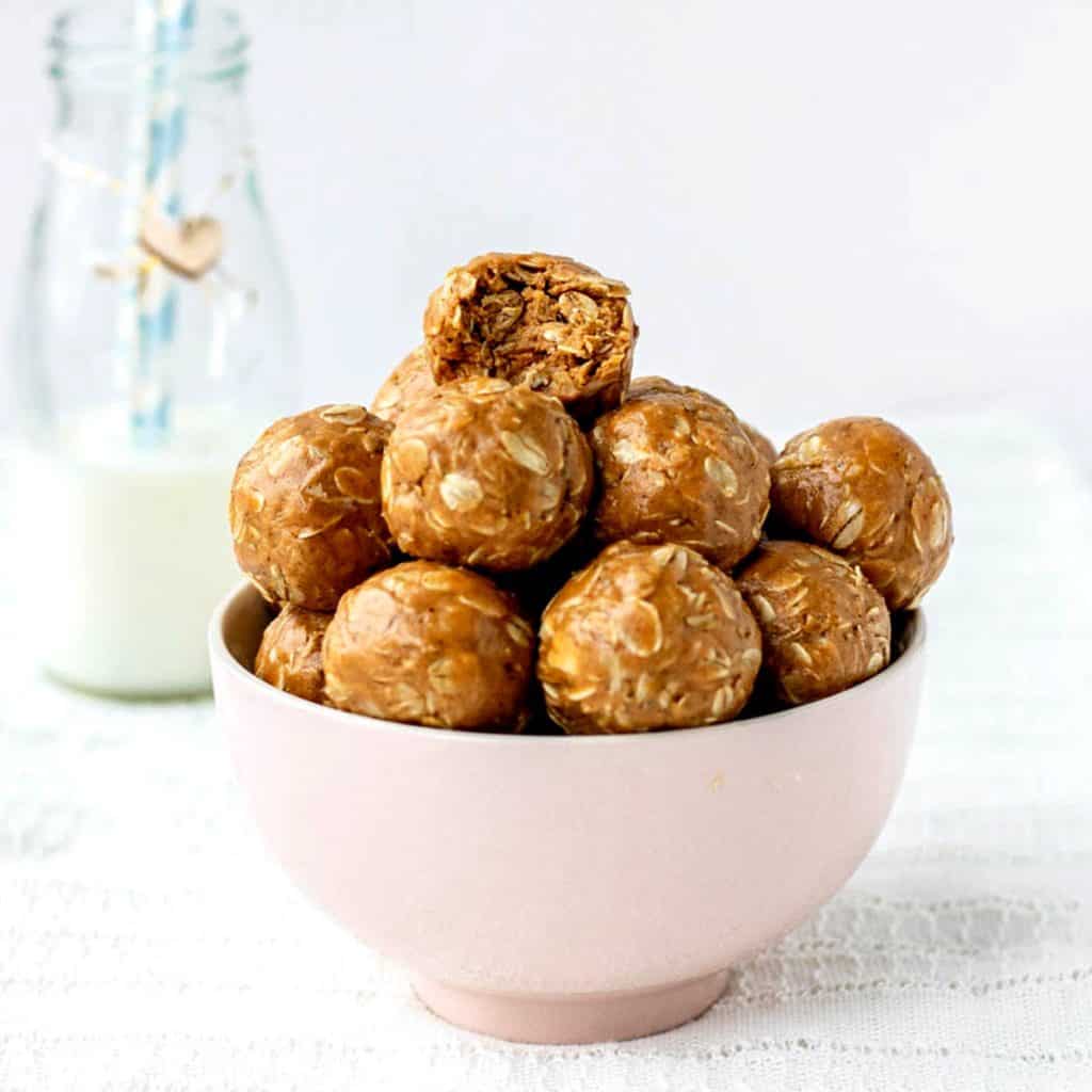 3 ingredient peanut butter oatmeal balls in a bowl with a bite taken out of the top ball.