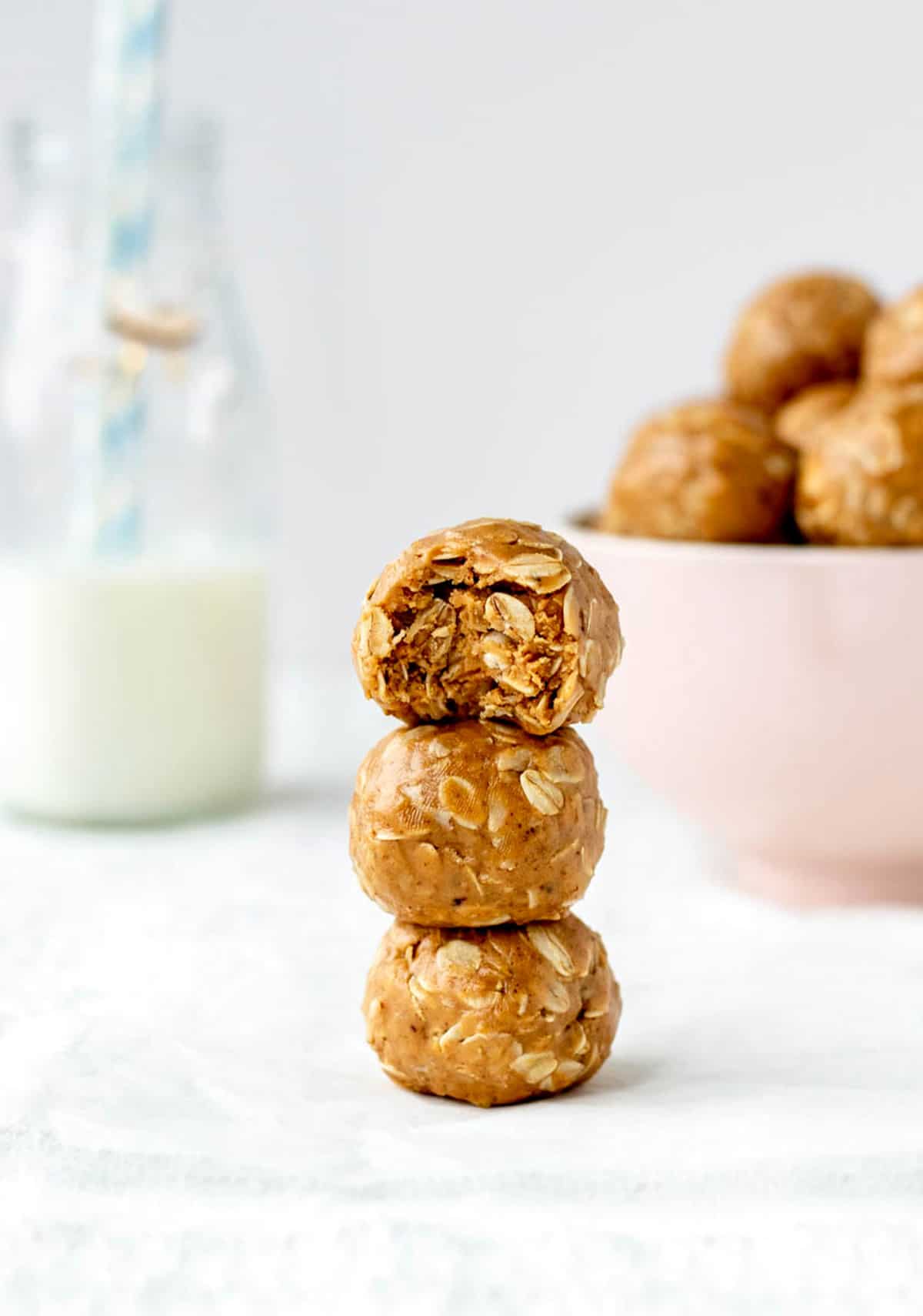 A stack of three peanut butter oatmeal balls with a bite taken out of the top one.