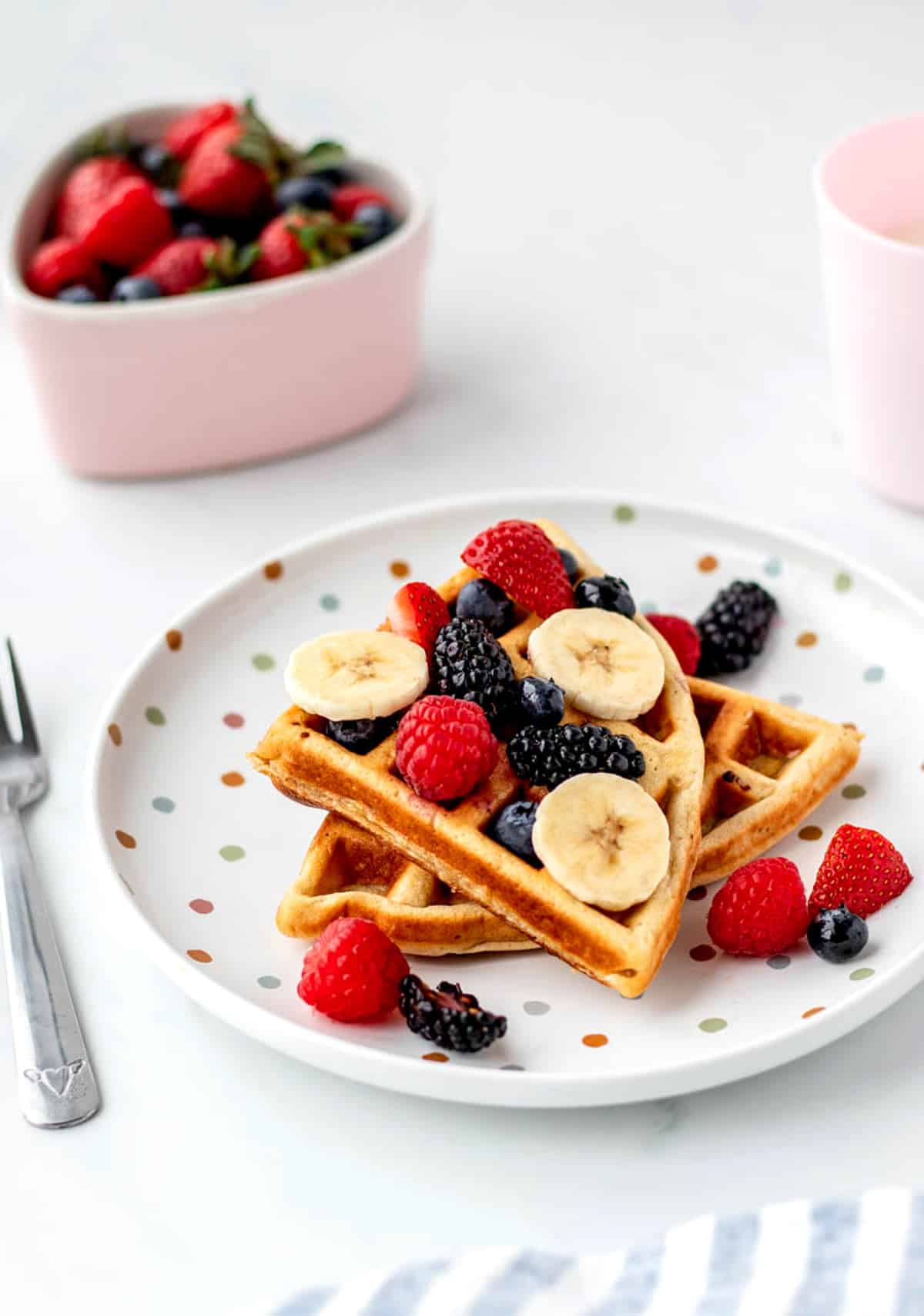 3-ingredient protein waffles on a polka dot plate topped with berries and bananas.