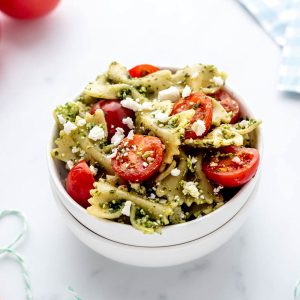 A small bowl of 4 ingredient pasta salad with pesto, feta and tomatoes.
