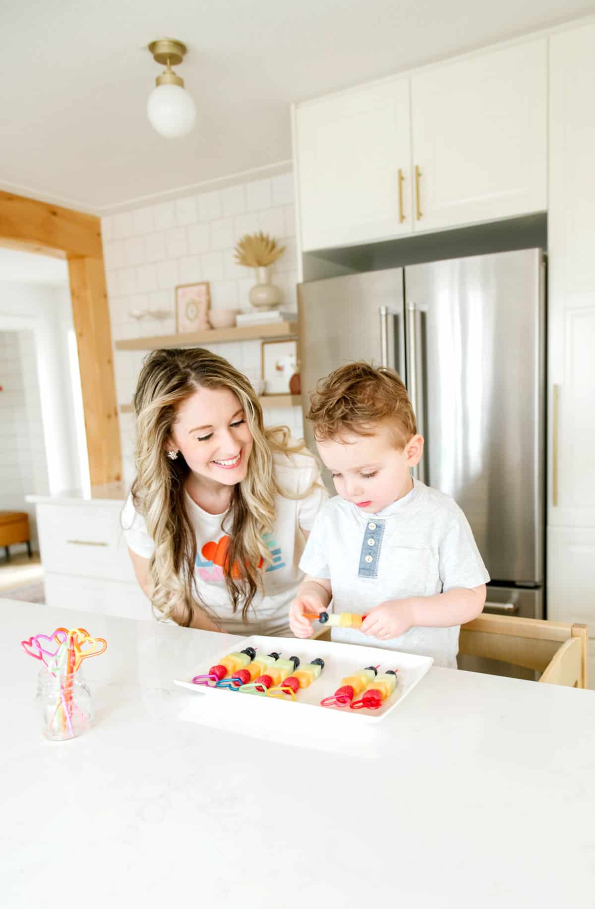 Elysia and her son making rainbow fruit skewers.