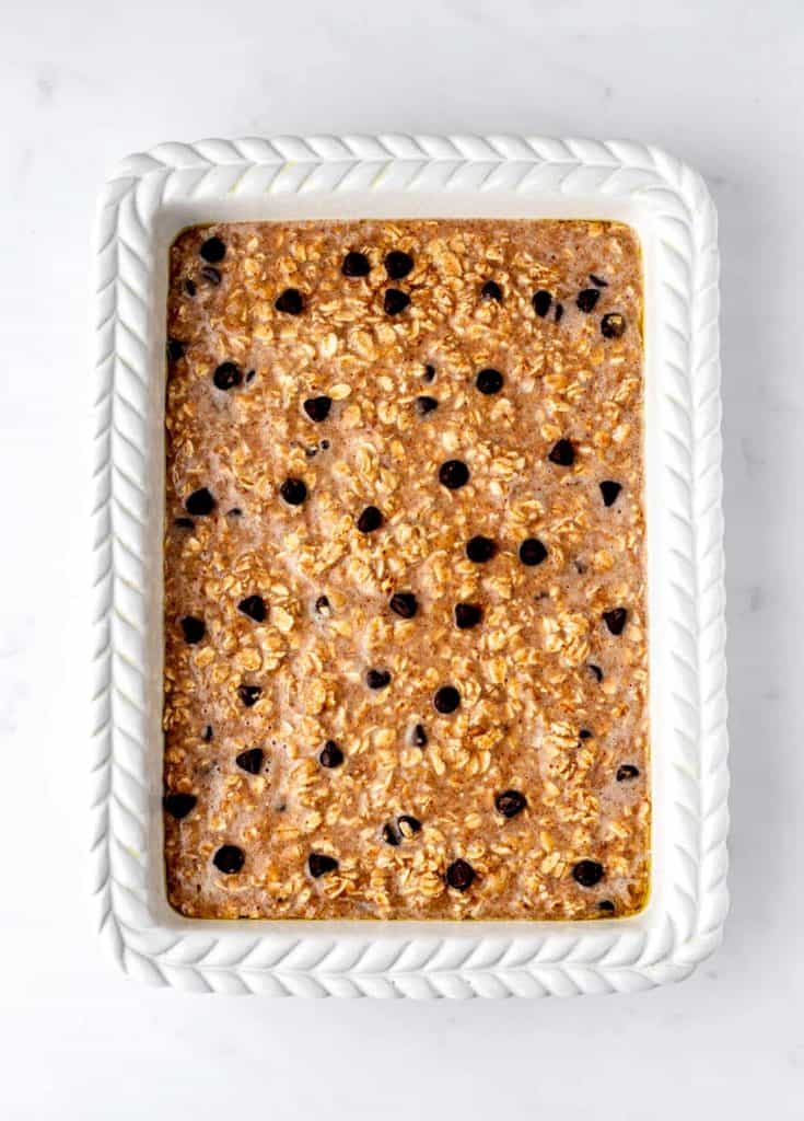 The uncooked chocolate chip baked oatmeal mixture in a white baking dish.