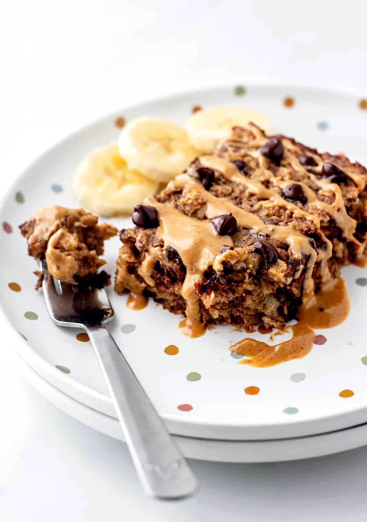 A slice of baked oatmeal with chocolate chips, peanut butter and banana slices.