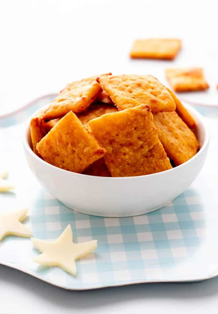 A white bowl filled with healthy crackers served with star shaped cheese.