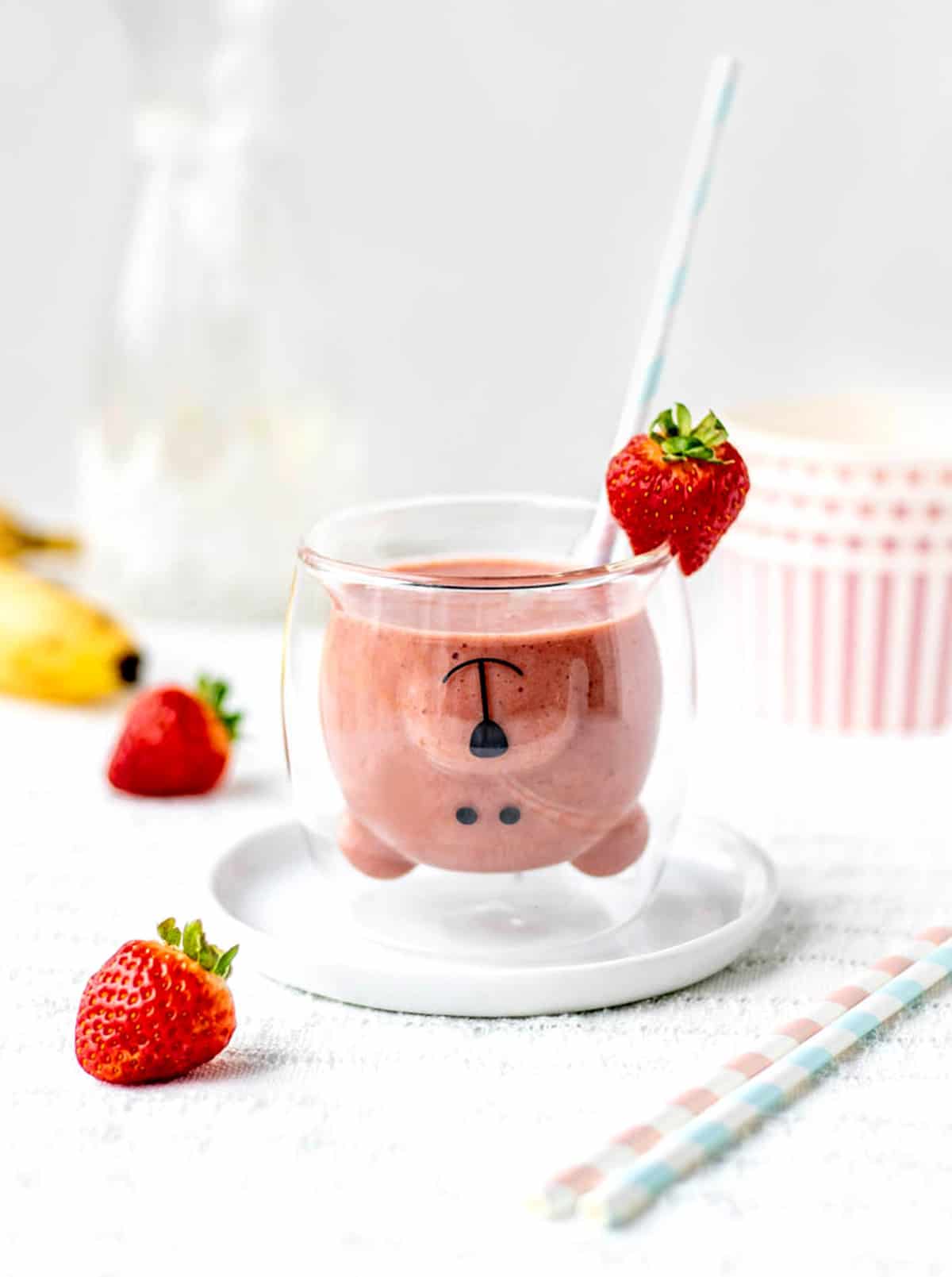 The strawberry banana smoothie without yogurt in a teddy glass with a straw.
