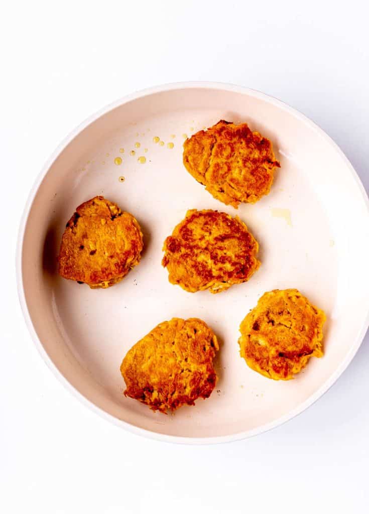 Cooked sweet potato fritters in a fryer pan.
