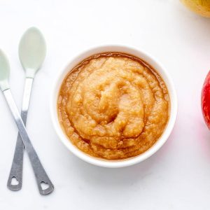 Overhead image of a bowl of homemade unsweetened applesauce next to two spoons.