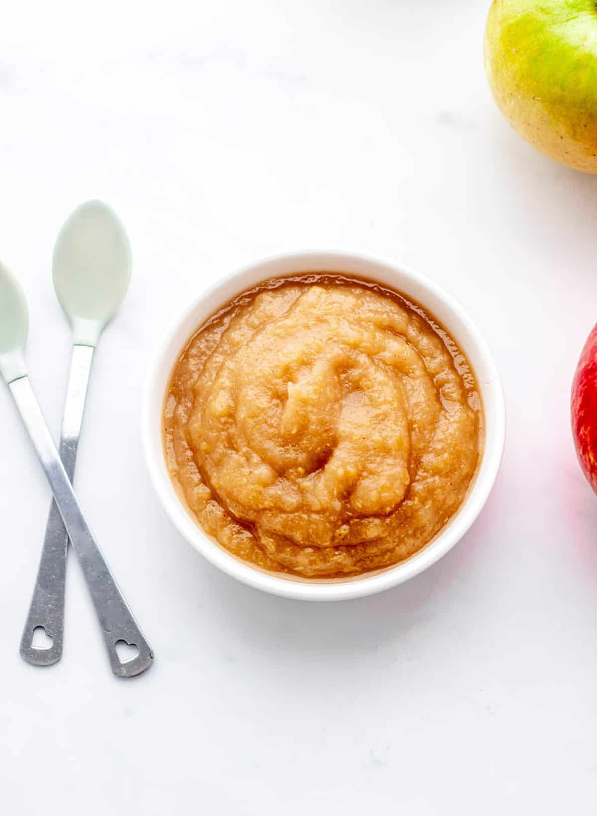 An overhead shot of sugar free applesauce next to two spoons.