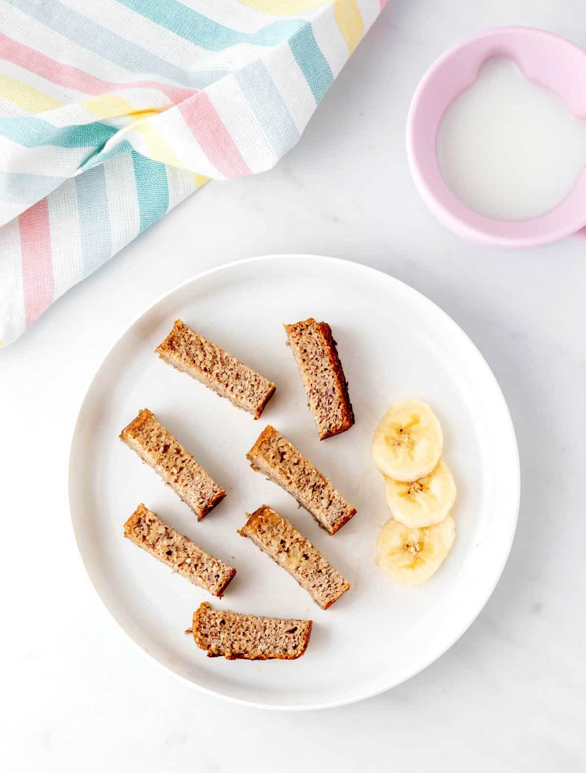 A plate with banana bread cut into thin slices for baby led weaning.