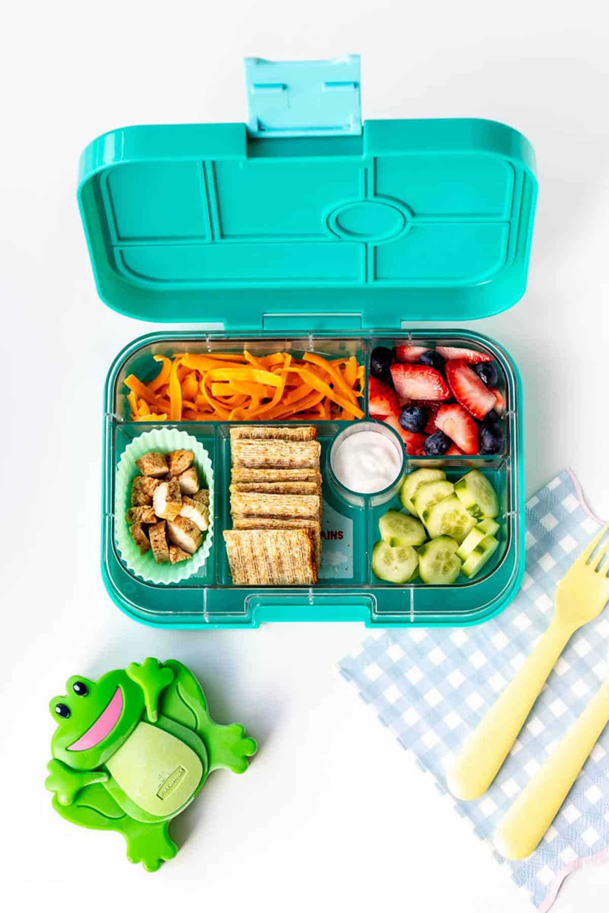 A frog ice pack next to a packed lunch box.