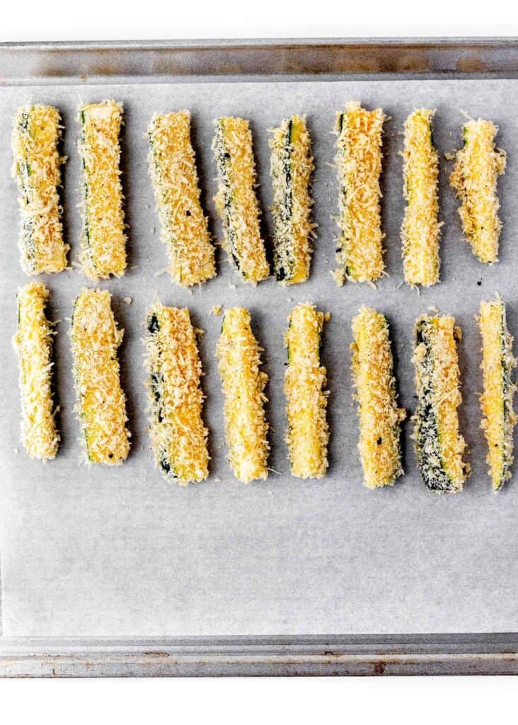 Uncooked zucchini fries on a baking sheet.