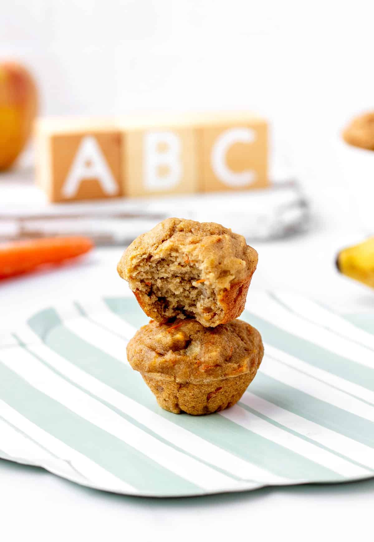 Two mini naturally sweetened apple banana carrot muffins stacked on top of eachother.