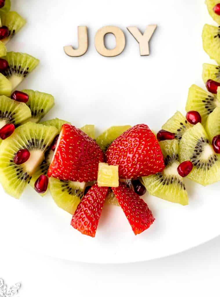 An up close image of the strawberry bow on the bottom of the holiday fruit wreath.