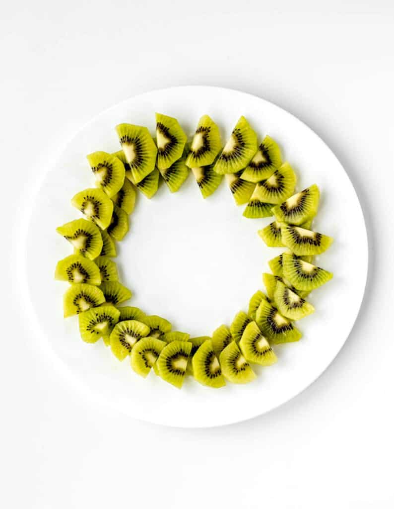 Kiwi slices assembled into the shape of a Christmas fruit wreath.