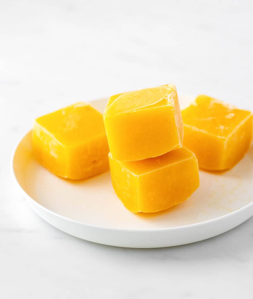 Frozen mango puree cubes on a plate.