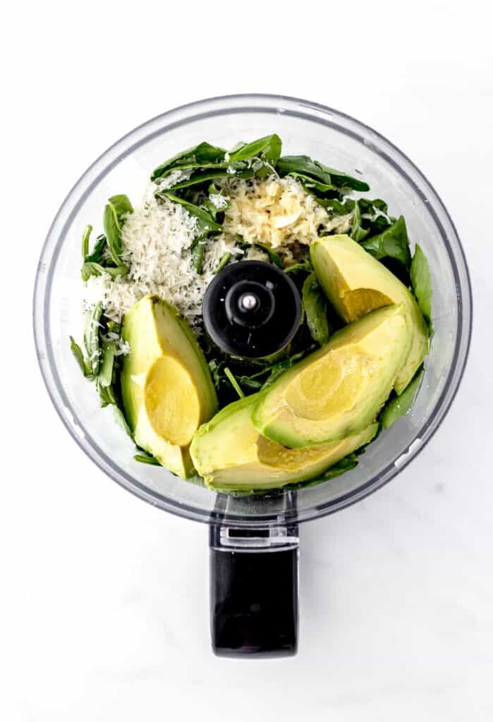 Ingredients for the avocado pesto sauce in a food processor.