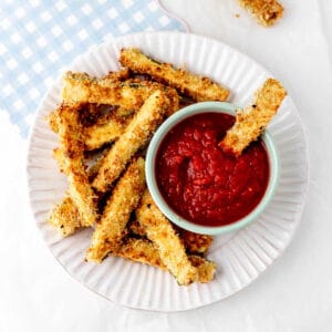 A plate with air fryer zucchini fries and marina sauce.