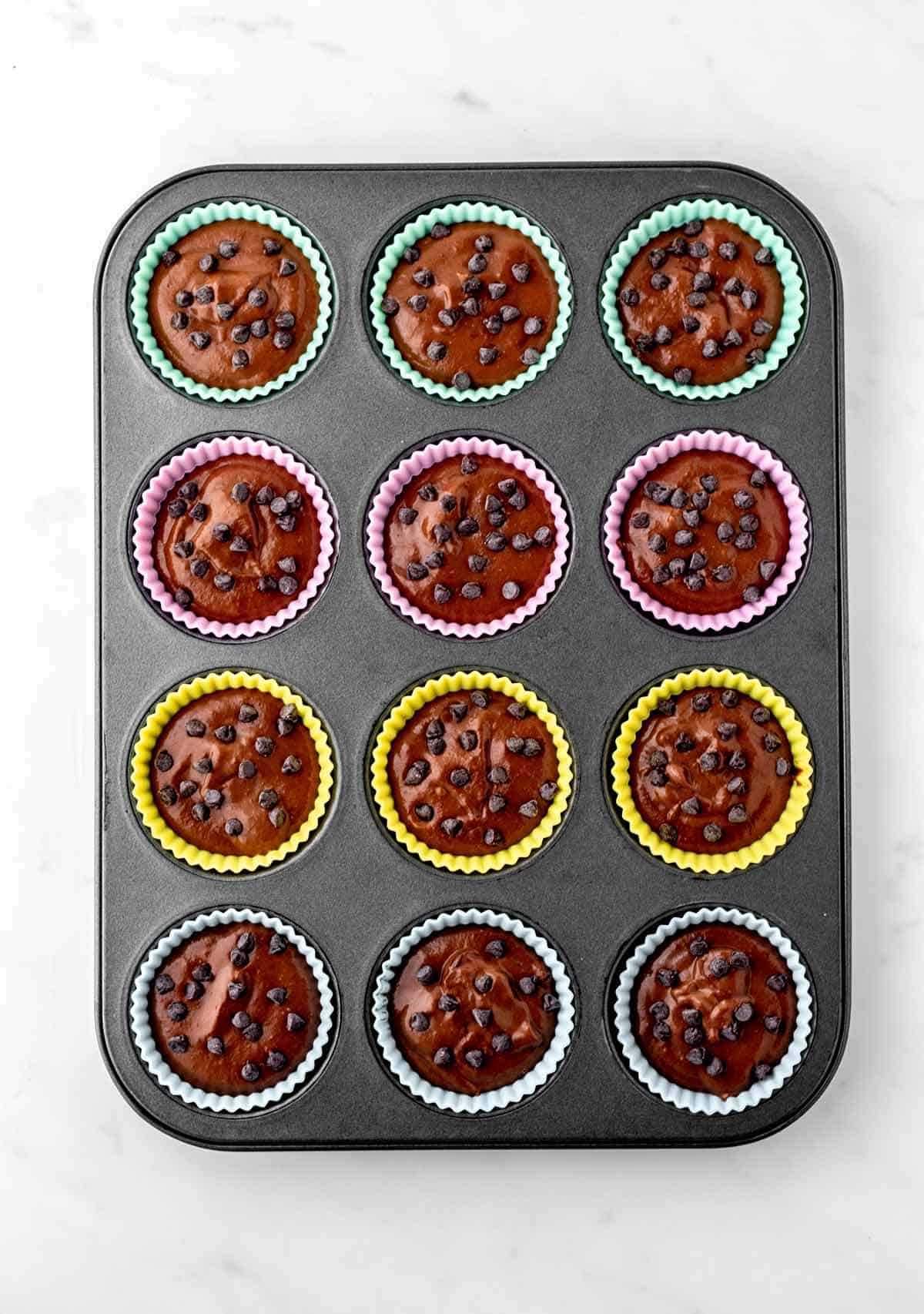 The 3-ingredient brownie batter divided into silicone muffin cups in a muffin tin.