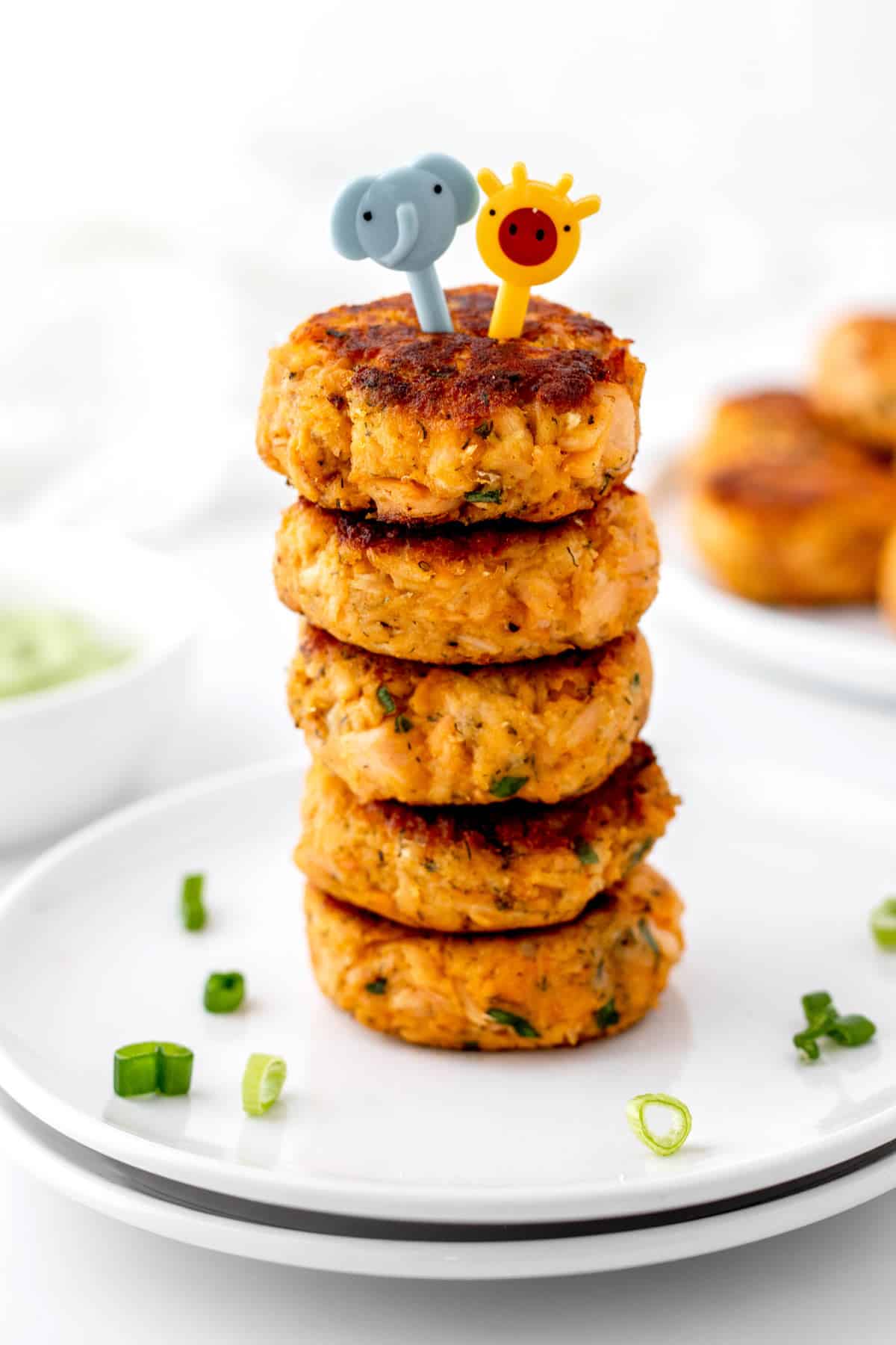 A close up image of a stack of baby salmon cakes topped with cute little picks.