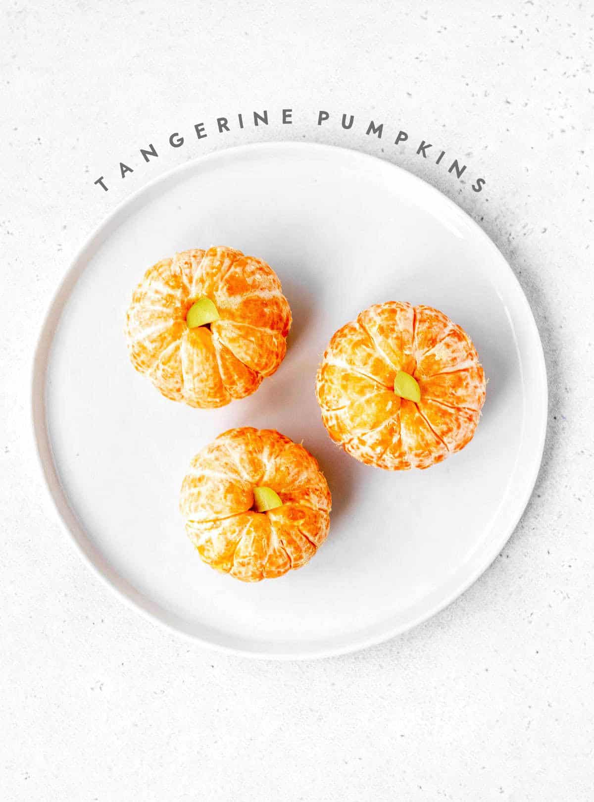Tangerine pumpkins on a white plate.