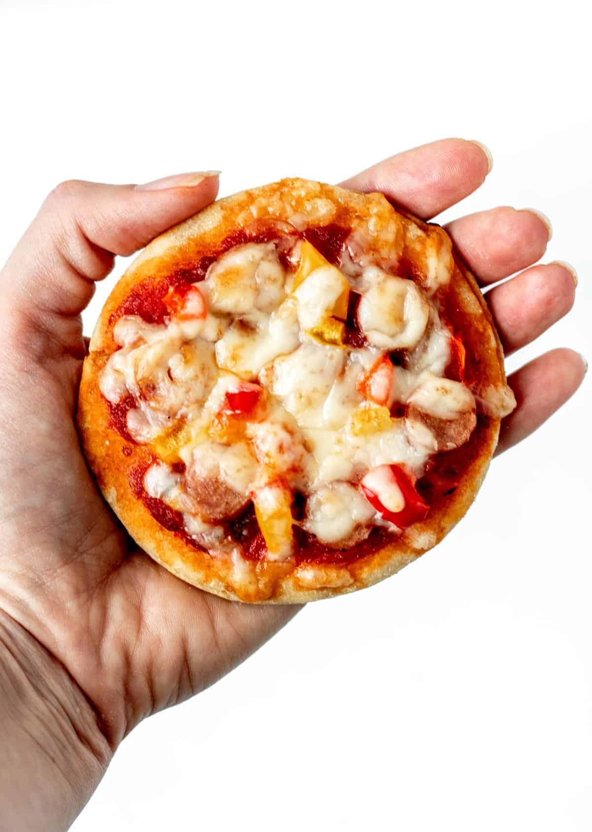 A hand holding up a healthy mini pizza.