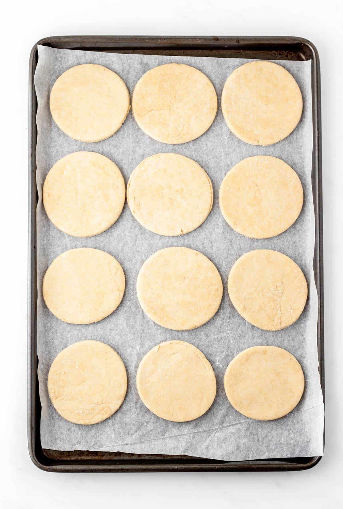 Mini dough circles on a baking sheet.