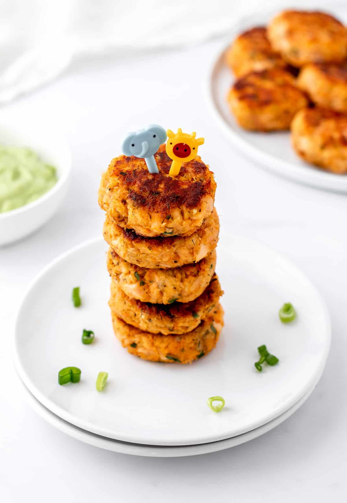 A stack of mini salmon cakes with little elephant and giraffe picks on top.