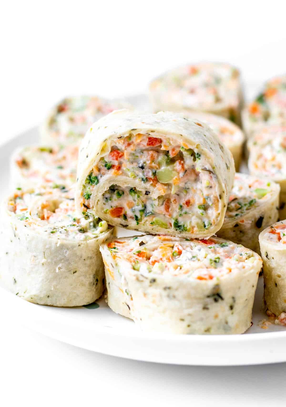 Close up image of a veggie tortilla pinwheel on a stack of other roll ups.