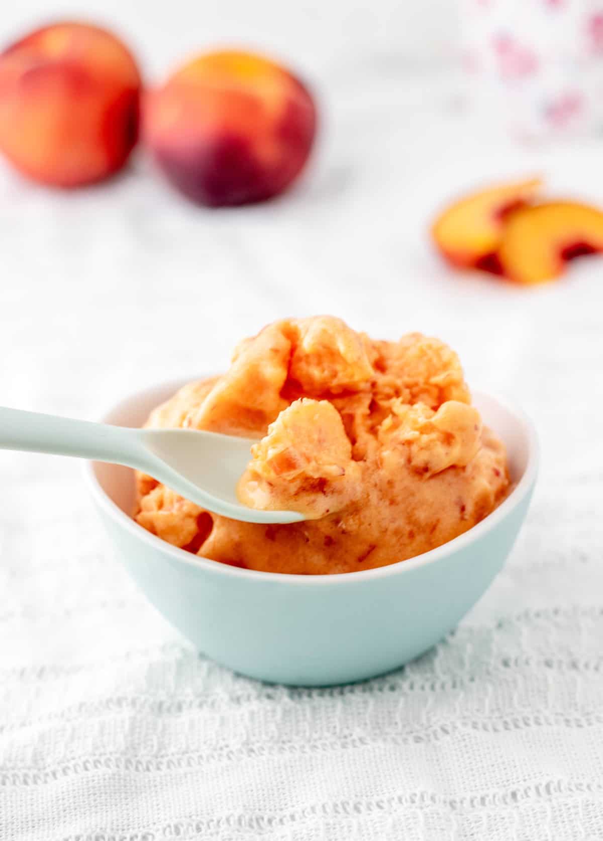 A spoon scooping up some homemade peach sorbet.