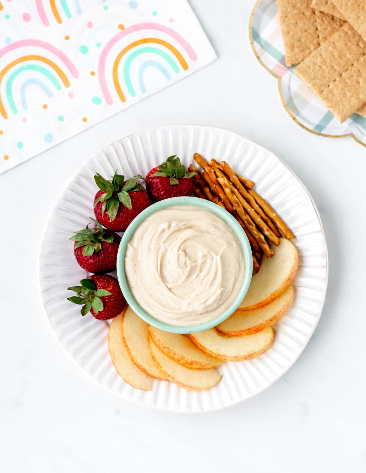 A plate with strawberries, apple slices, pretzels and 4-ingredient peanut butter dip.