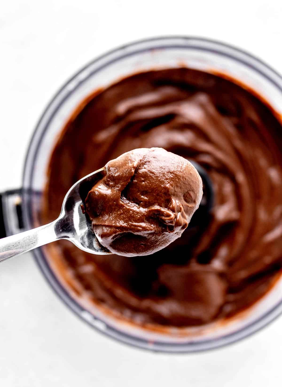 A spoon holding up some creamy chocolate avocado pudding.