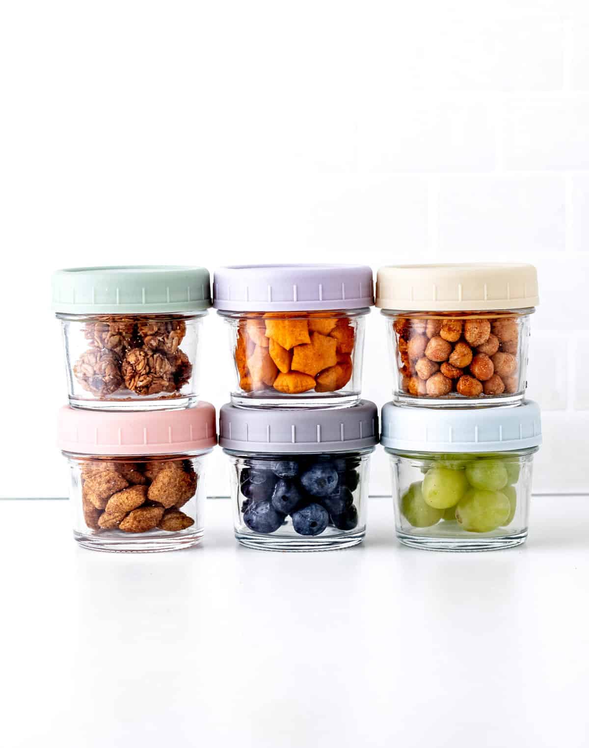Six small containers stacked with healthy road trip snacks for kids.