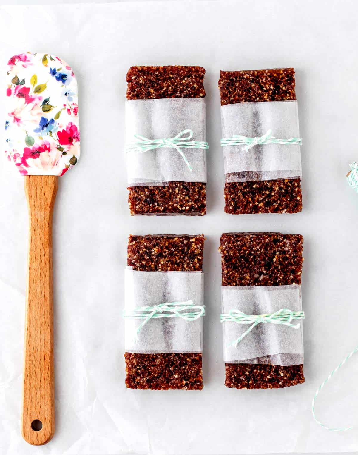 Four homemade pressed fruit bars wrapped in parchment paper and string.