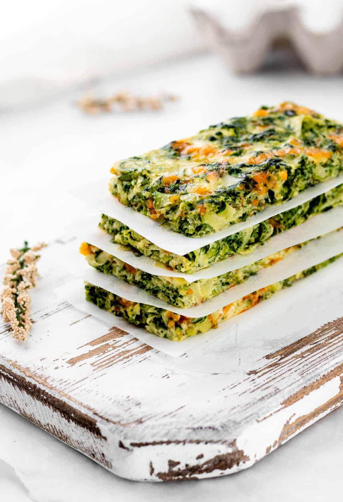 Four baked spinach zucchini egg fingers stacked on top of each other.