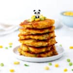 A stack of easy healthy corn fritters on a white plate with a bear pick.