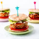 Three mini turkey burger sliders on colorful plates with star picks.