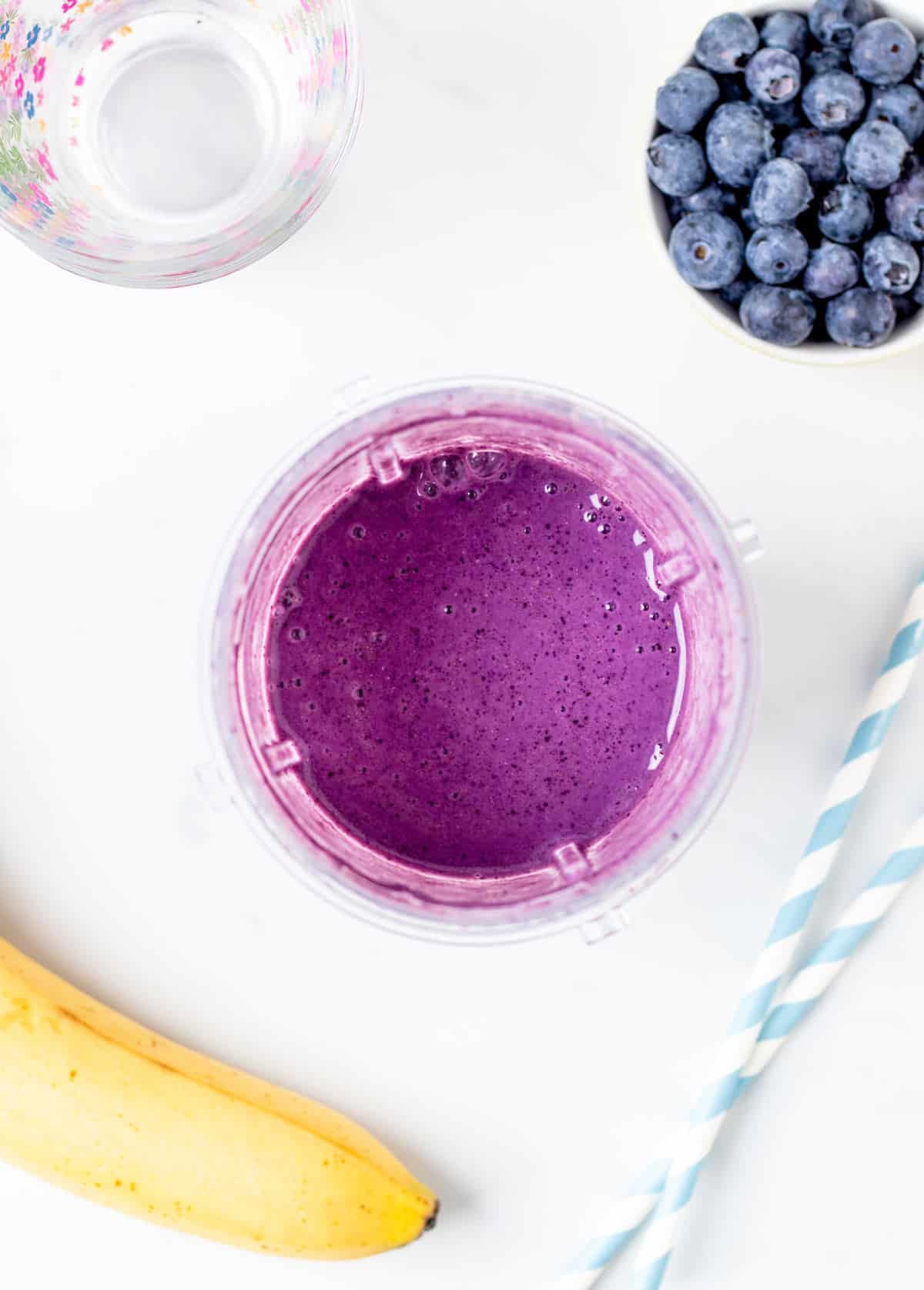 Overhead shot of a fruit smoothie in a Ninja blender cup with blueberries and bananas.