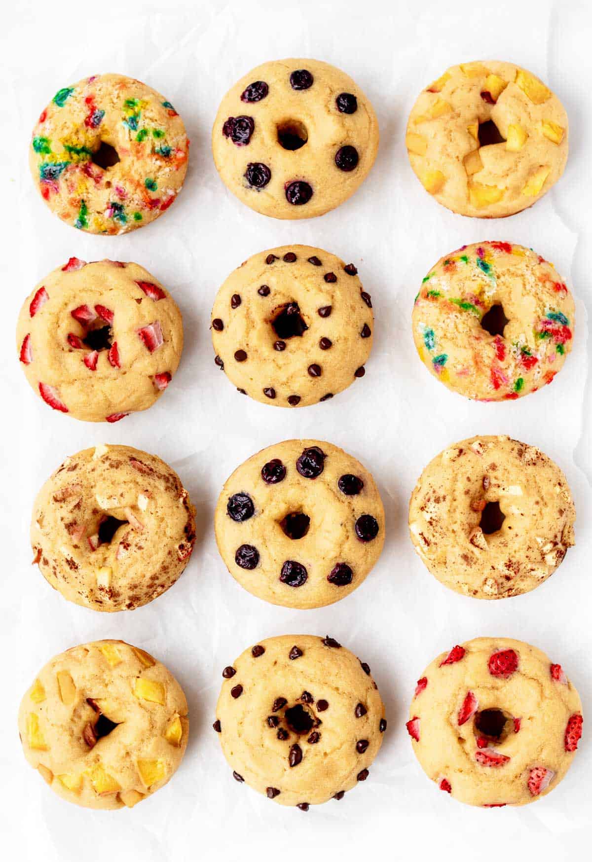 Twelve pancake donuts with different toppings.