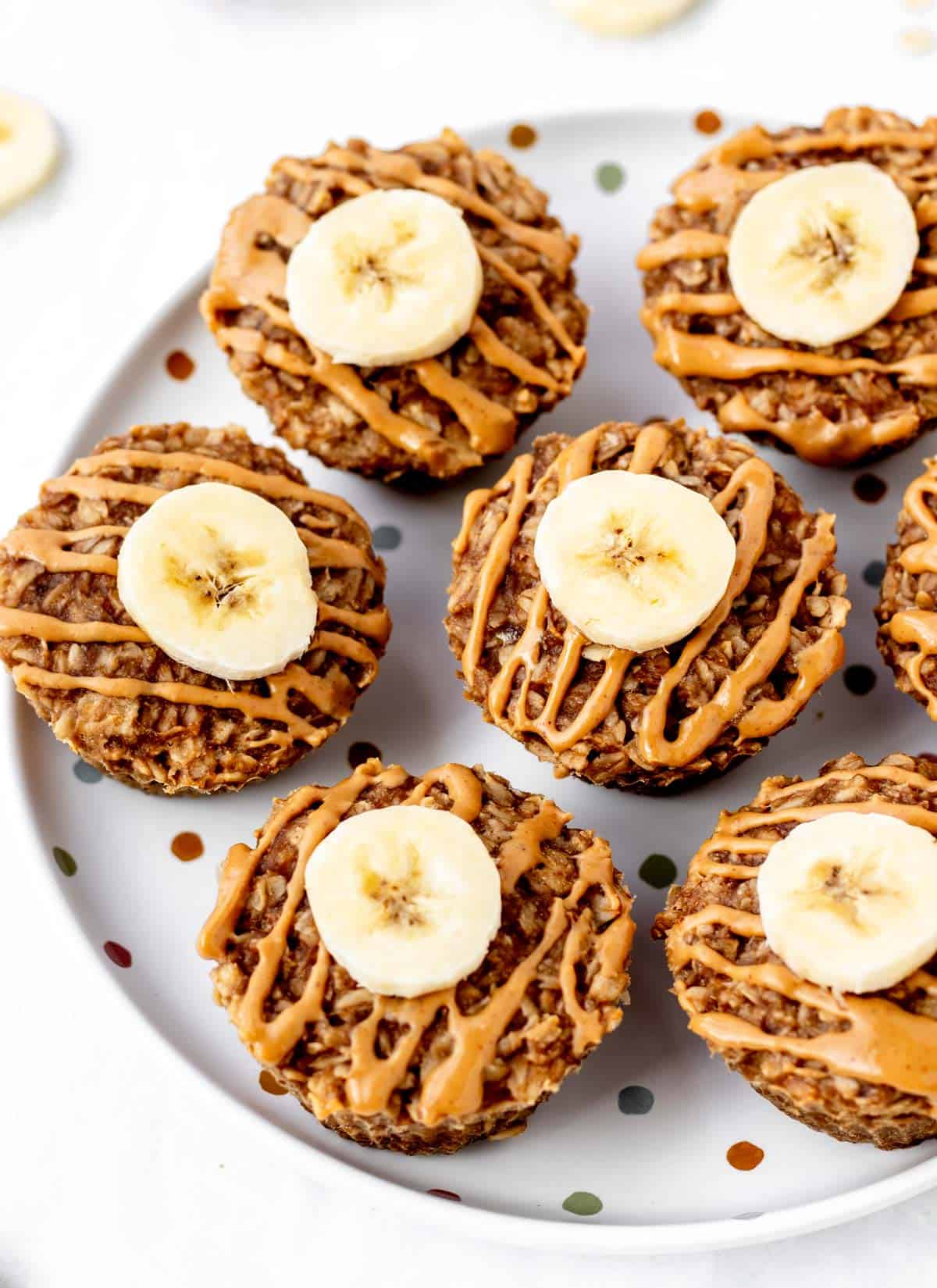 A plate of 3 ingredient banana muffins topped with peanut butter and banana slices.