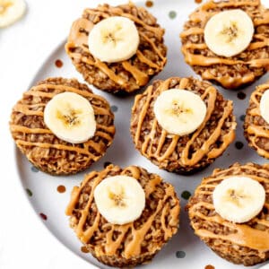 Banana oatmeal muffins on a polka dot plate with peanut butter and banana slices.