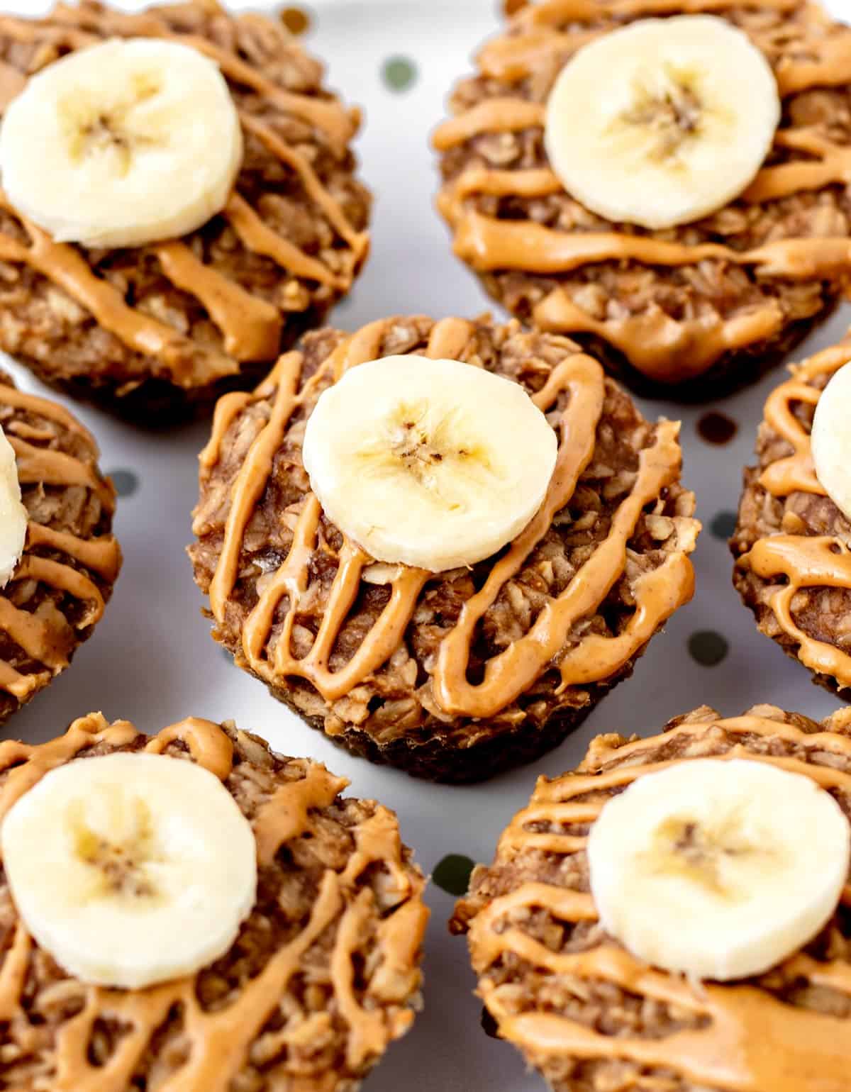 Close up image of a plate of 3-ingredient banana oatmeal muffins topped with peanut butter and banana slices.