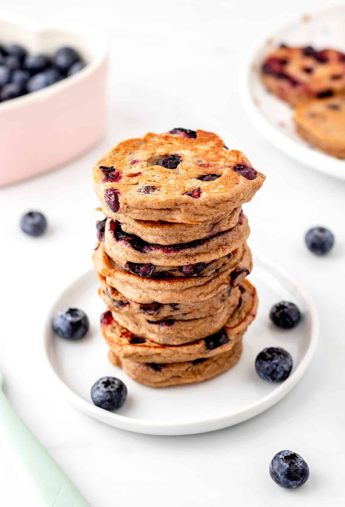 A stack of baby blueberry pancakes on a white plate.