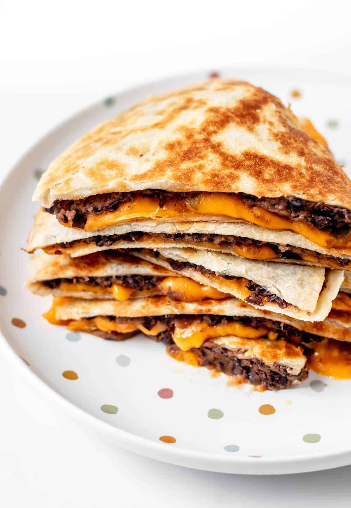 A stack of baby led weaning quesadillas on a polka dot plate.