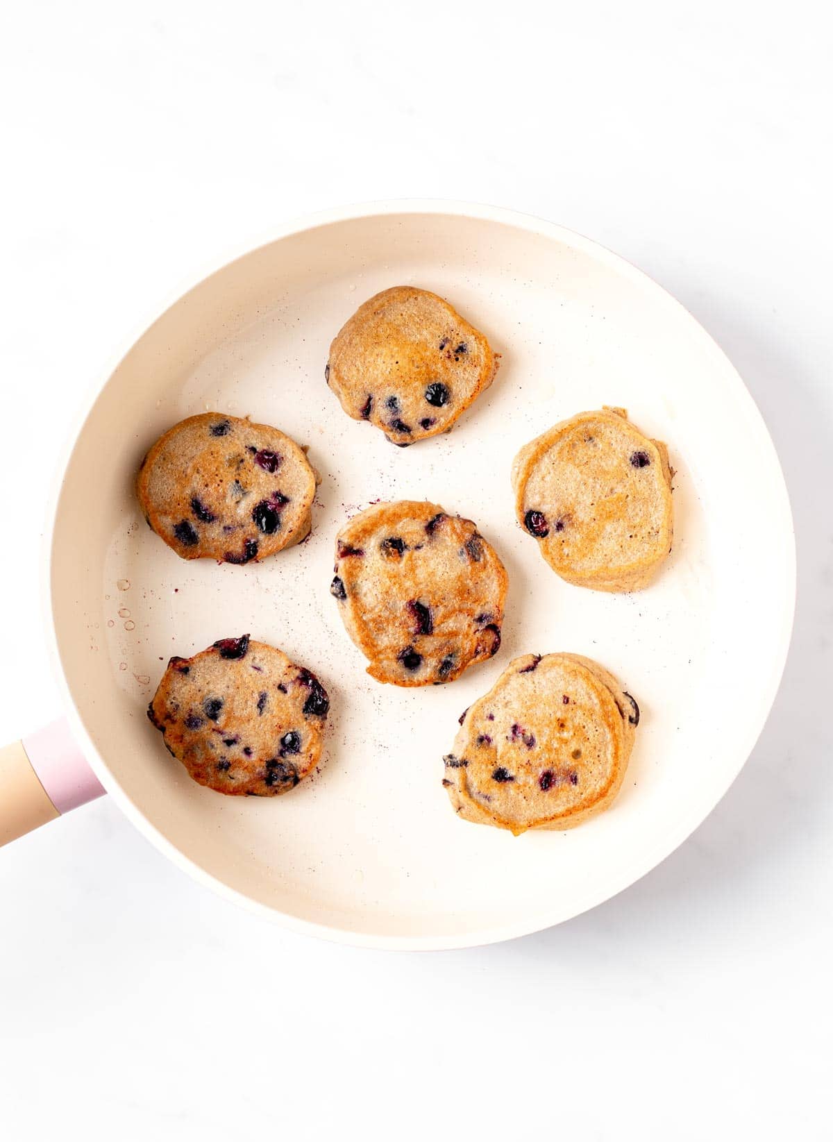 Cooked baby blueberry pancakes in a pan.