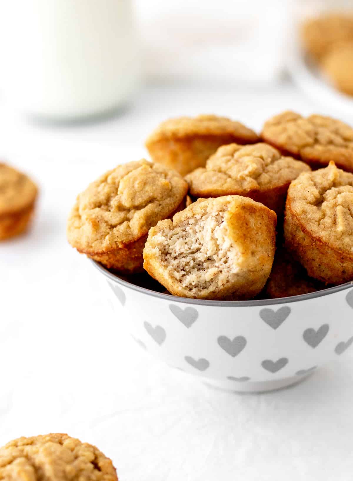Mini banana bread muffins in a white bowl with gray hearts.