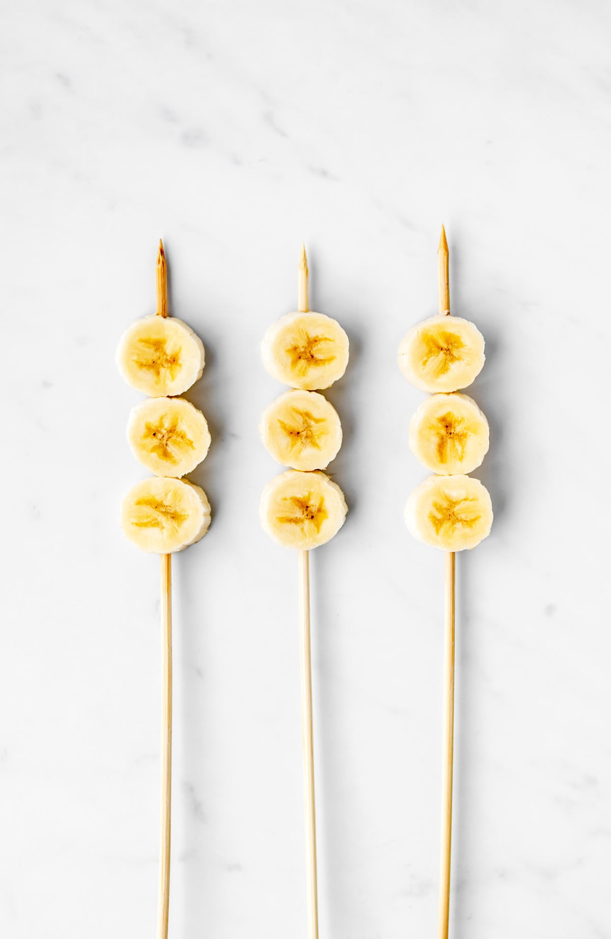 Three sticks with three banana slices on each one.