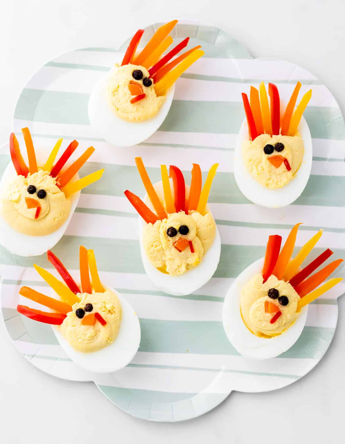 Overhead image of turkey deviled eggs on a striped plate.