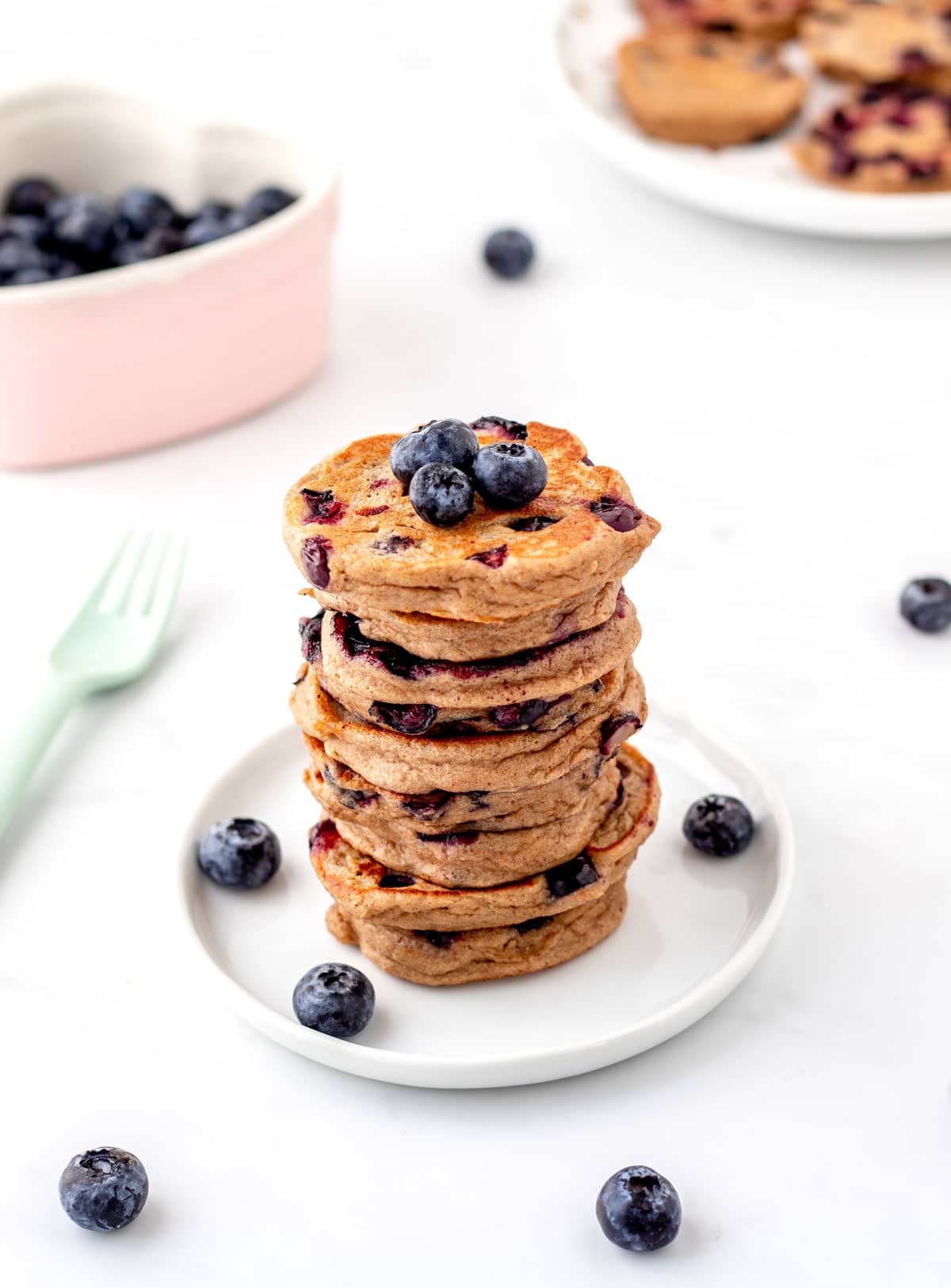 Mini blueberry pancakes stacked on a small white plate.